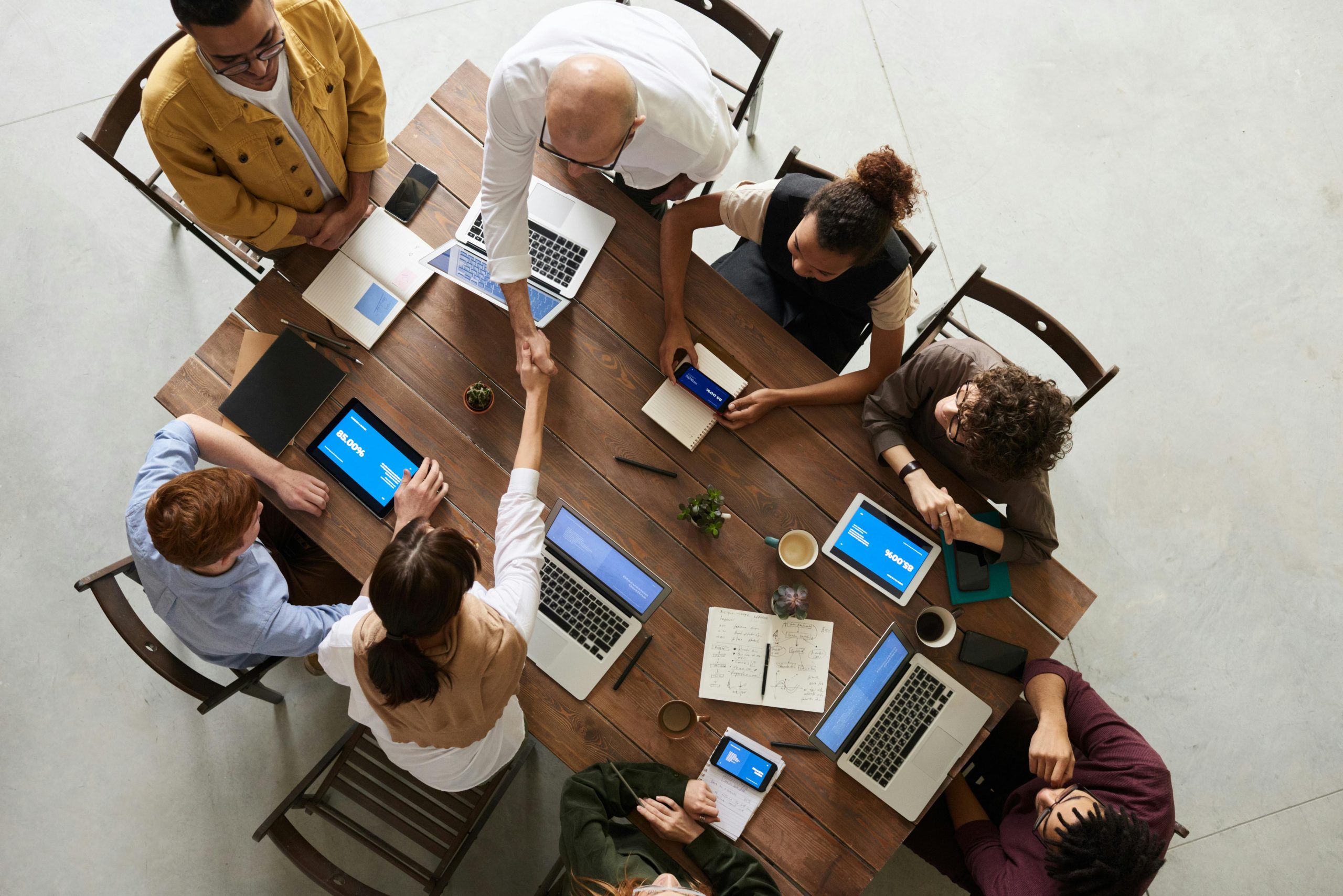 Company employees sitting around a table with their laptops open.