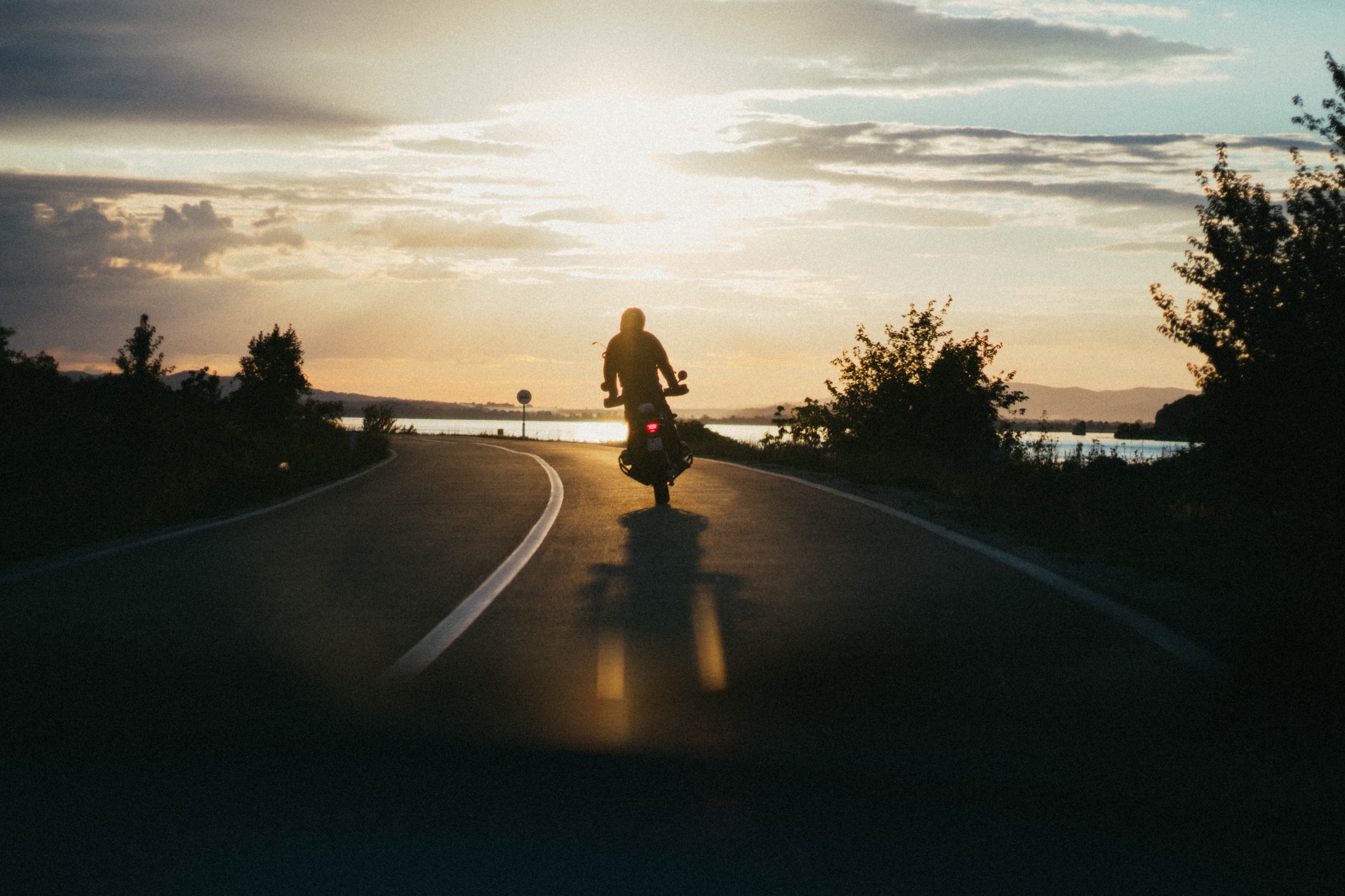 Person on motorcycle riding in sunset.